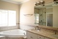 This Master Bath has an elegant whirlpool soaking tub with stylish filler valve, a double adult height marble sink vanity with oil rubbed valves, a beautiful oversized clear glass shower, and a private water closet room for the busy but demanding couple.